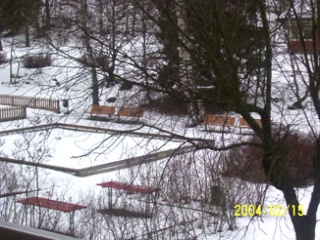 Bild på en lekplats bakom träd i snö