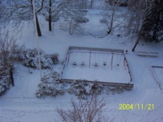 Bild högt uppifrån på gungor och staket i snö